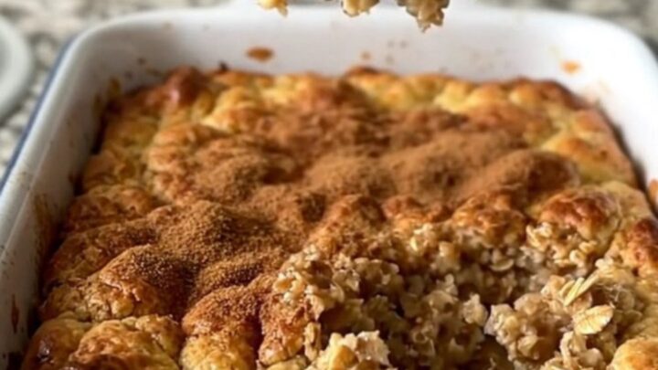 A golden, freshly baked oatmeal dish in a white rectangular baker on a granite countertop.