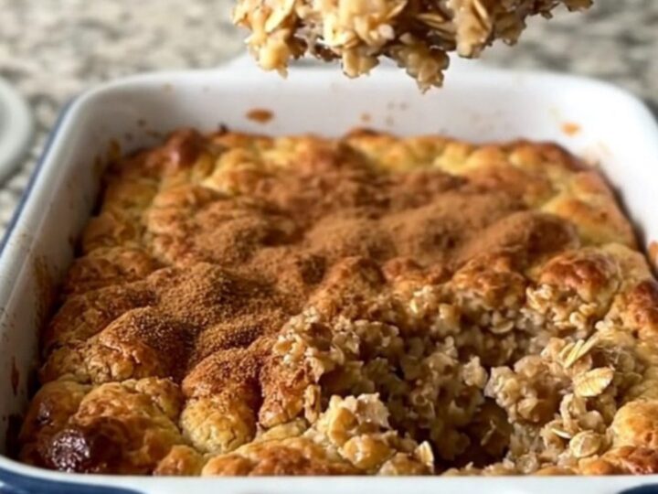 A golden, freshly baked oatmeal dish in a white rectangular baker on a granite countertop.