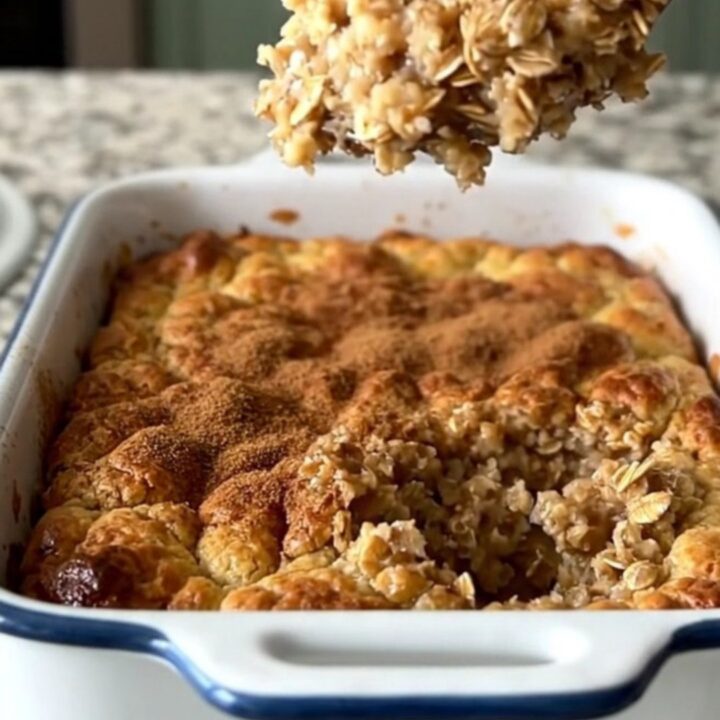 A golden, freshly baked oatmeal dish in a white rectangular baker on a granite countertop.