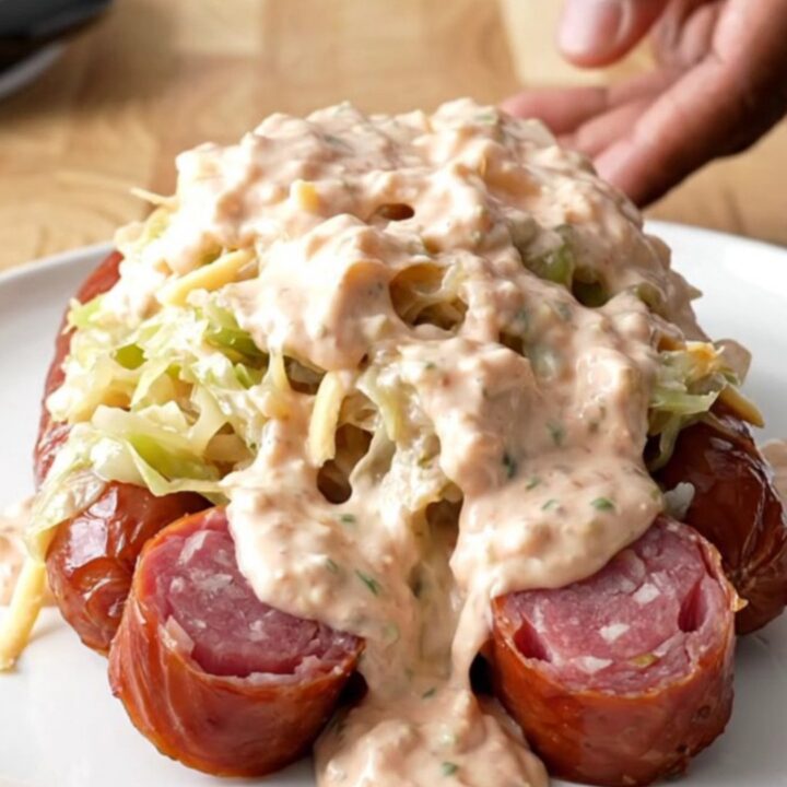 A top-down view of a slow cooker filled with layers of sliced kielbasa, sauerkraut, Swiss cheese