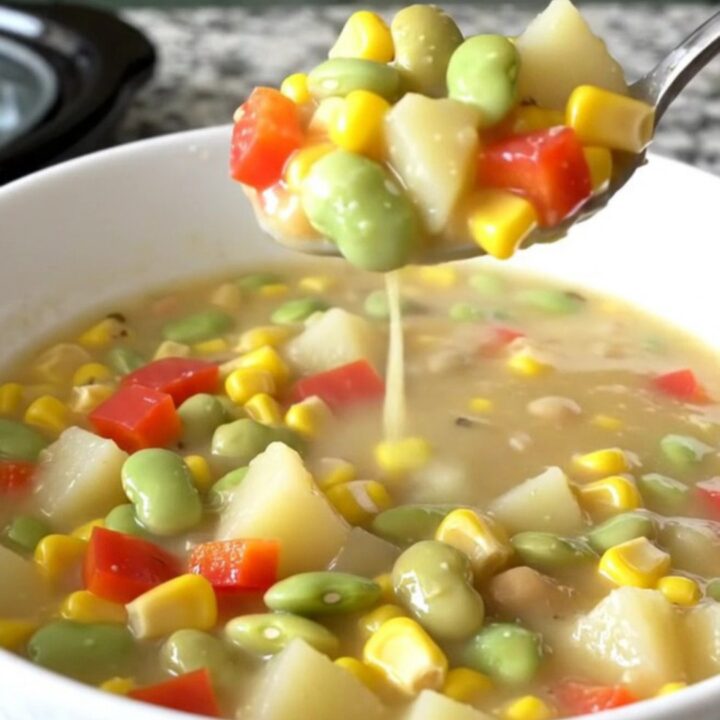 A shallow white bowl filled with creamy succotash chowder featuring corn, beans, and potatoes.