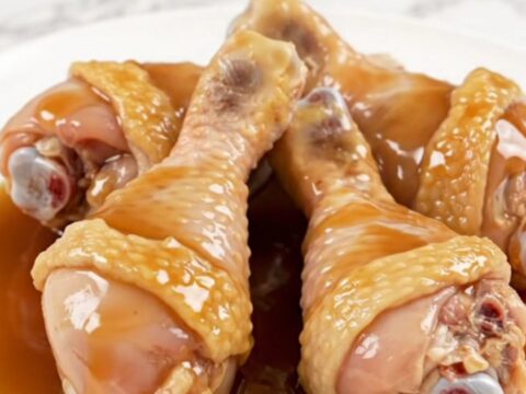 A close-up of maple garlic chicken drumsticks served on a white plate with a glossy, dark sauce.