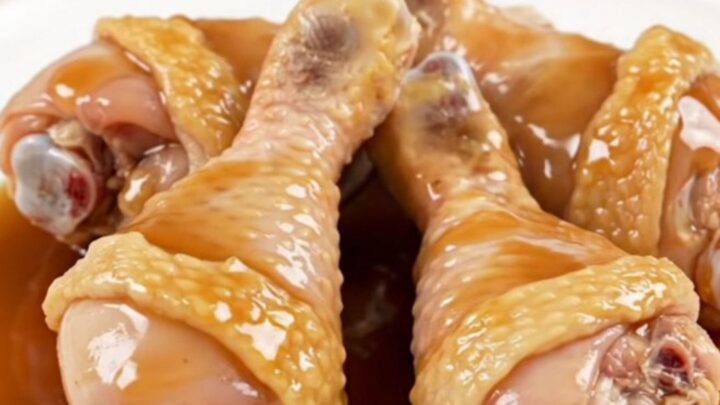 A close-up of maple garlic chicken drumsticks served on a white plate with a glossy, dark sauce.