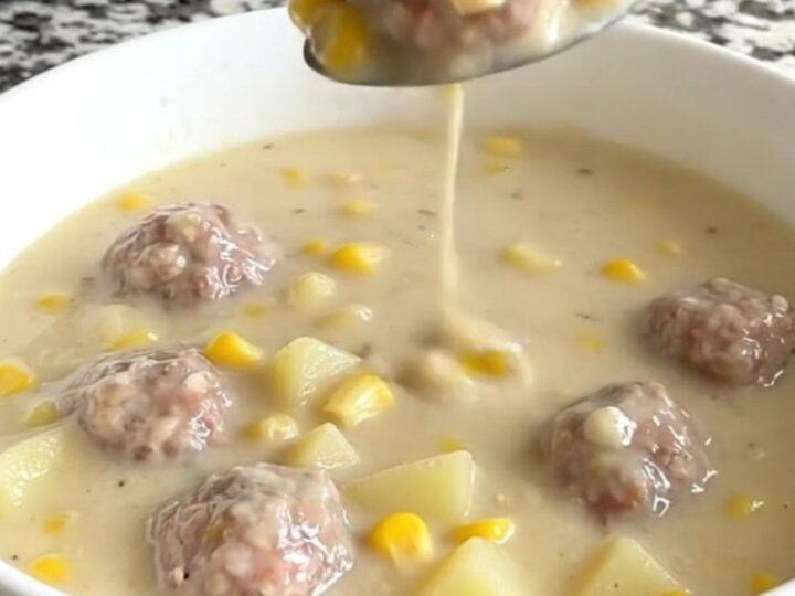 A close-up of a creamy turkey meatball and corn chowder in a white bowl.