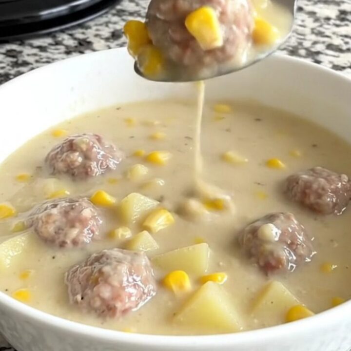 A close-up of a creamy turkey meatball and corn chowder in a white bowl.
