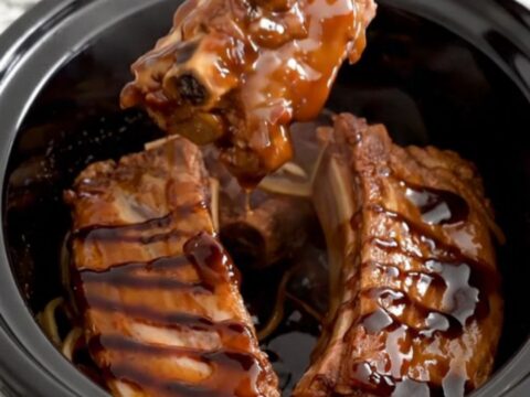 A close-up of tender boneless country-style pork ribs coated in a rich, dark honey balsamic glaze in a slow cooker.