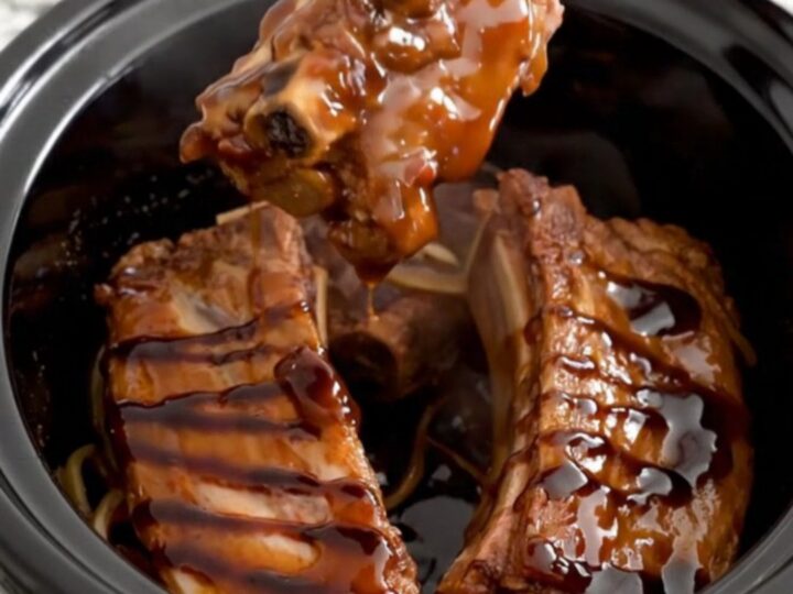 A close-up of tender boneless country-style pork ribs coated in a rich, dark honey balsamic glaze in a slow cooker.