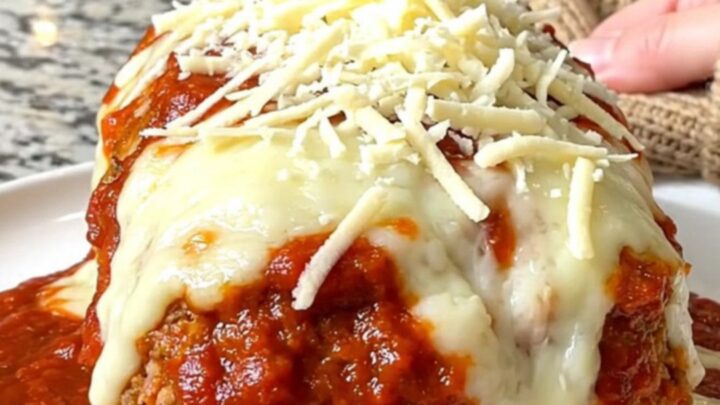 A whole, oval-shaped turkey meatloaf topped with rich marinara sauce and melted mozzarella cheese in a slow cooker.