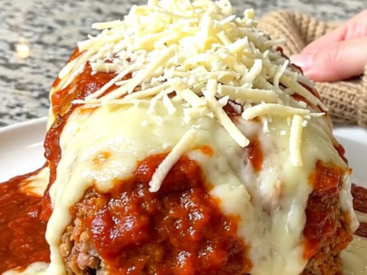 A whole, oval-shaped turkey meatloaf topped with rich marinara sauce and melted mozzarella cheese in a slow cooker.
