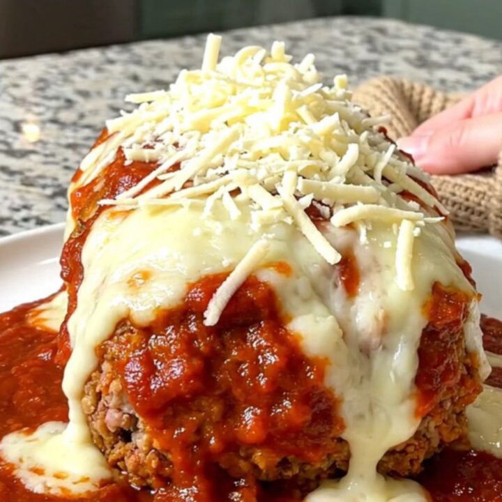 A whole, oval-shaped turkey meatloaf topped with rich marinara sauce and melted mozzarella cheese in a slow cooker.
