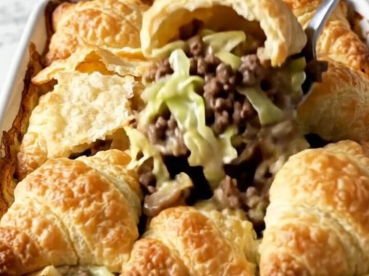 A top-down view of a Cabbage Burger Crescent Bake in a white baking dish with golden crescent rolls on top.