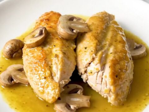 A close-up shot of slow-cooked chicken breasts smothered in a creamy Dijon mushroom sauce.