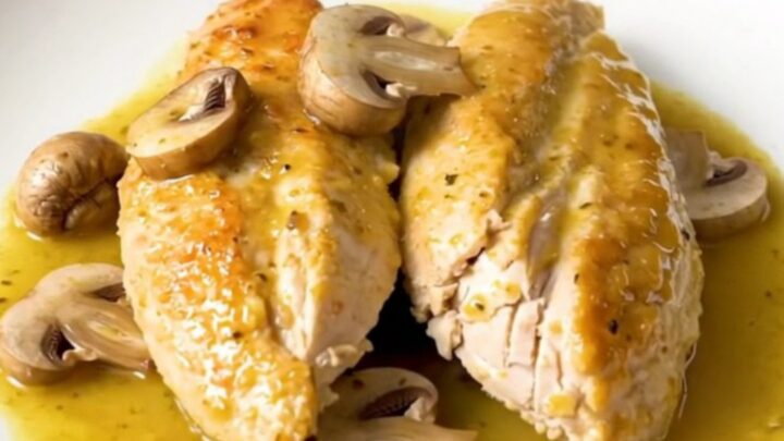 A close-up shot of slow-cooked chicken breasts smothered in a creamy Dijon mushroom sauce.