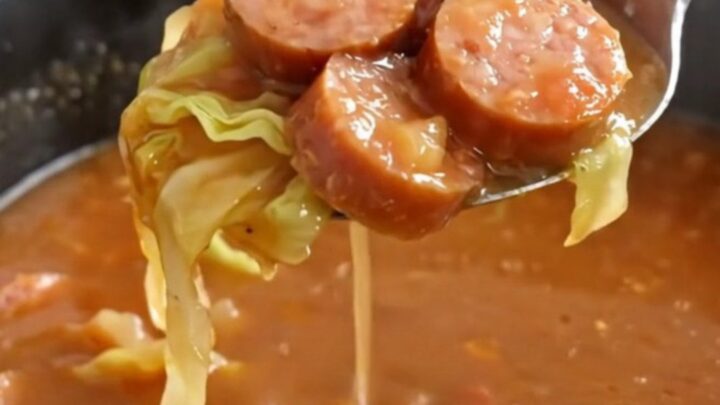 A bowl of steaming unstuffed cabbage soup with smoked sausage coins and tender cabbage in a rich tomato broth.