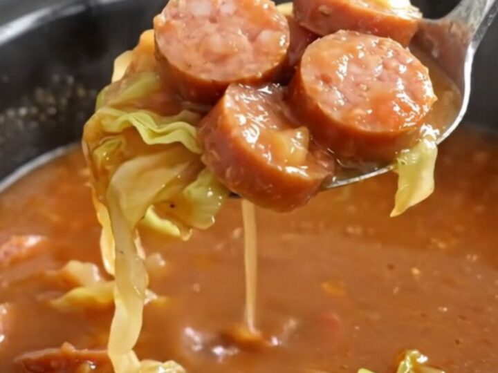 A bowl of steaming unstuffed cabbage soup with smoked sausage coins and tender cabbage in a rich tomato broth.