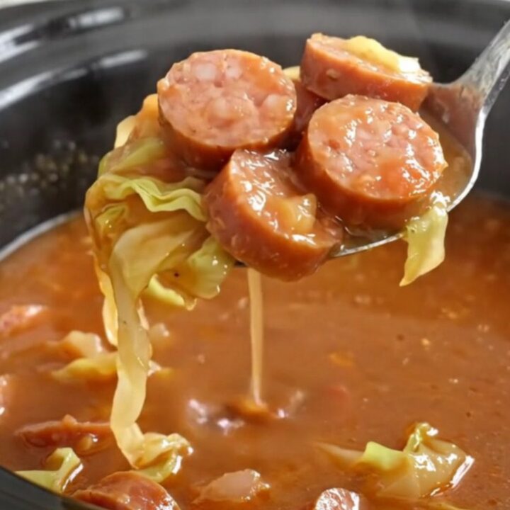 A bowl of steaming unstuffed cabbage soup with smoked sausage coins and tender cabbage in a rich tomato broth.