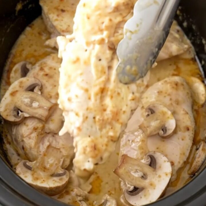 A close-up of tender chicken breasts served in a creamy mushroom sauce, garnished with a sprinkle of paprika.