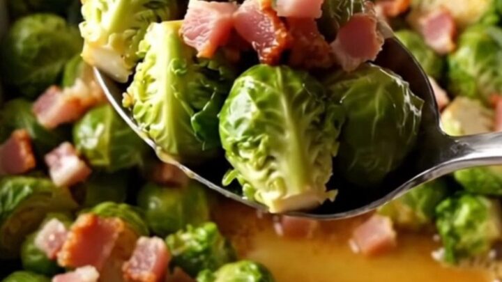 A large white rectangular baking dish filled with roasted Brussels sprouts and crispy bacon pieces.