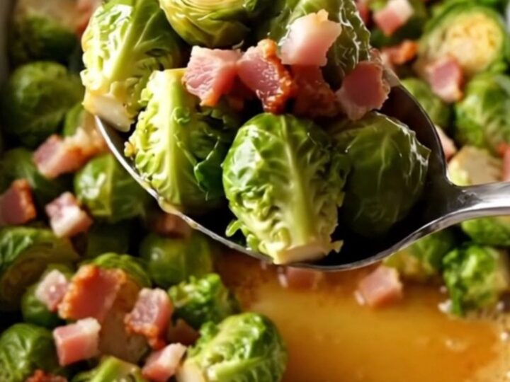 A large white rectangular baking dish filled with roasted Brussels sprouts and crispy bacon pieces.