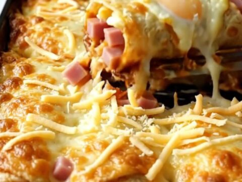 A top-down view of a rectangular ceramic baking dish filled with golden-brown breakfast enchiladas topped with melted cheese.