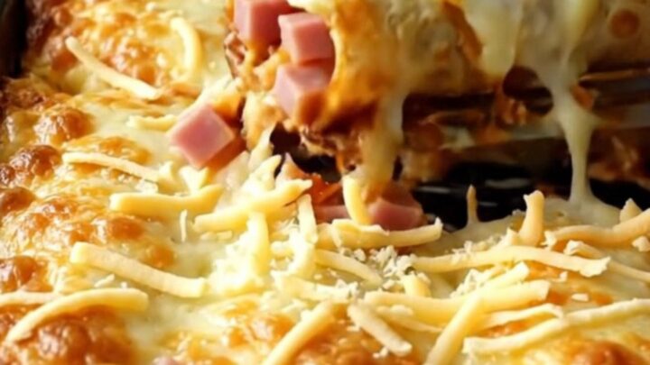 A top-down view of a rectangular ceramic baking dish filled with golden-brown breakfast enchiladas topped with melted cheese.