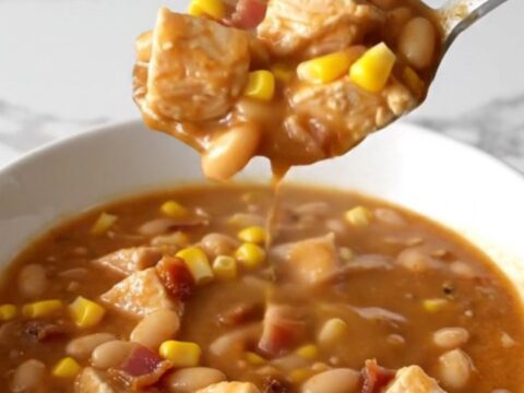 A bowl of creamy crack chicken chili topped with bacon bits and corn, showing a thick and savory texture.