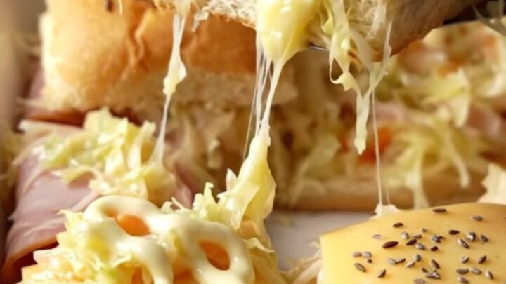 A golden-brown tray of turkey Reuben sliders with melted Swiss cheese and caraway seeds.