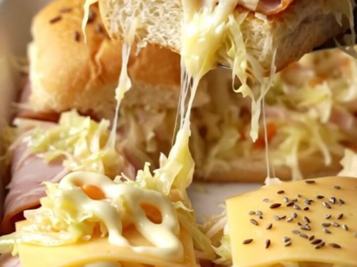 A golden-brown tray of turkey Reuben sliders with melted Swiss cheese and caraway seeds.