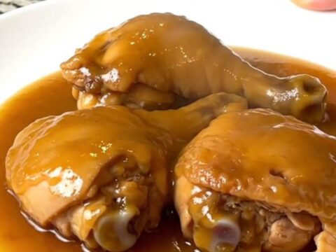 Tender boneless skinless chicken thighs coated in a glossy amber duck sauce in a slow cooker.
