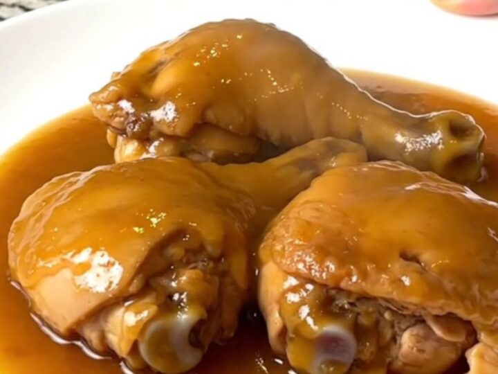 Tender boneless skinless chicken thighs coated in a glossy amber duck sauce in a slow cooker.