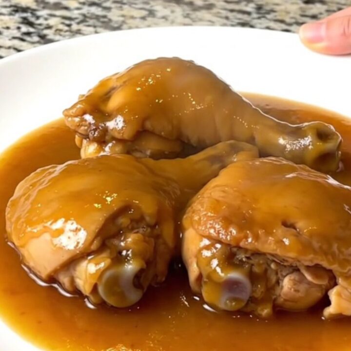 Tender boneless skinless chicken thighs coated in a glossy amber duck sauce in a slow cooker.