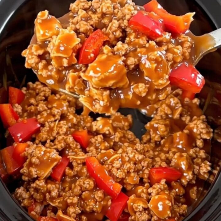 A close-up of slow-cooked ground turkey with red bell peppers in a glossy, spicy red sauce served in a bowl.