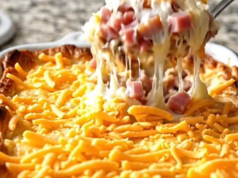 A top-down view of a creamy ham and cheddar mashed potato casserole in a rectangular white baker.