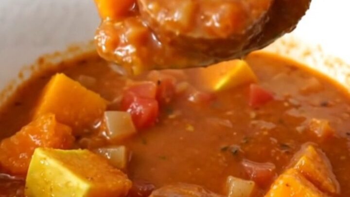 A close-up view of the slow cooker stew featuring sliced Italian sausage and tender butternut squash cubes in a rich tomato