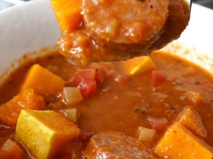A close-up view of the slow cooker stew featuring sliced Italian sausage and tender butternut squash cubes in a rich tomato