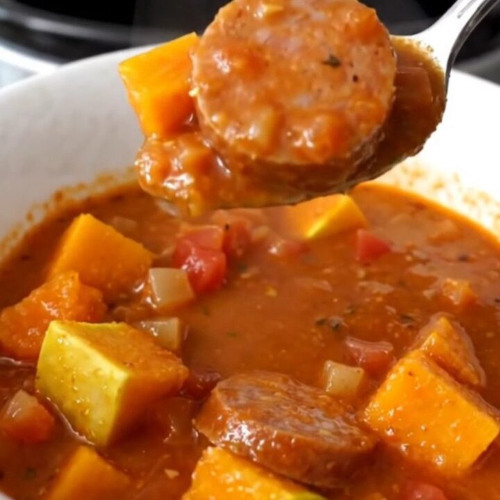 A close-up view of the slow cooker stew featuring sliced Italian sausage and tender butternut squash cubes in a rich tomato