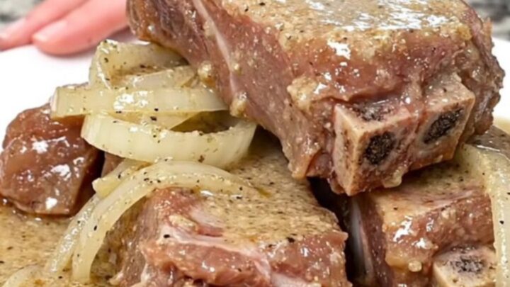 A plate of tender boneless country-style ribs smothered in a creamy, peppered white gravy with soft onion slices.