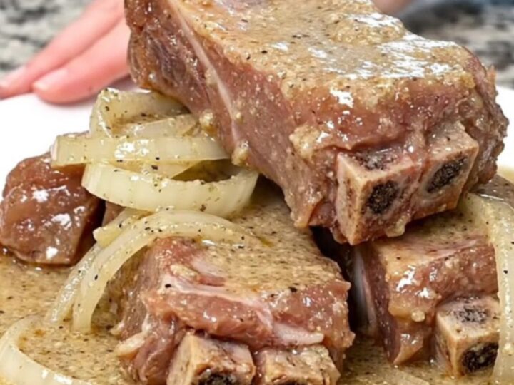 A plate of tender boneless country-style ribs smothered in a creamy, peppered white gravy with soft onion slices.