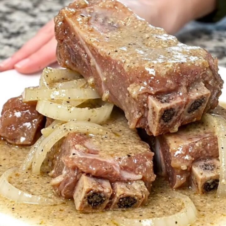 A plate of tender boneless country-style ribs smothered in a creamy, peppered white gravy with soft onion slices.