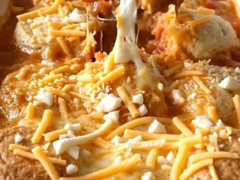 A golden-brown tomato soup and grilled cheese biscuit bake in a white ceramic dish.
