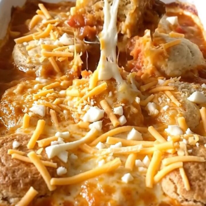 A golden-brown tomato soup and grilled cheese biscuit bake in a white ceramic dish.