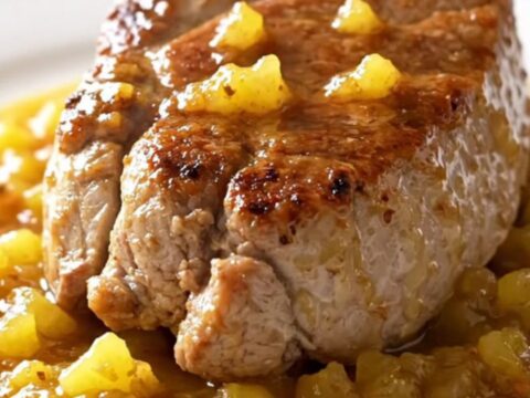 A slow cooker filled with pork tenderloin, pineapple chunks, and a rich, spiced jerk sauce.