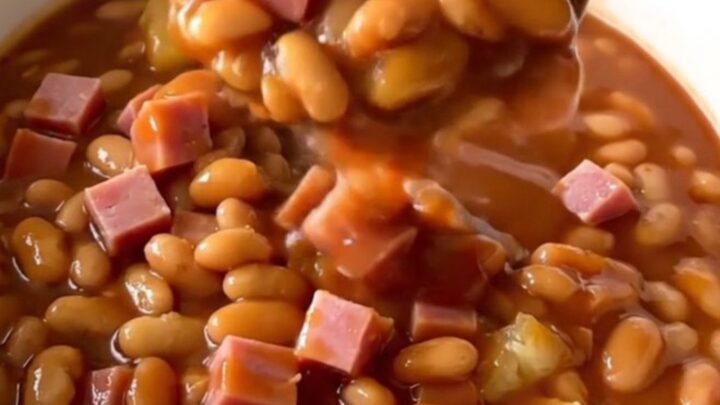 A top-down view of a slow cooker filled with diced ham, baked beans, pineapple chunks, and barbecue sauce ready to cook.