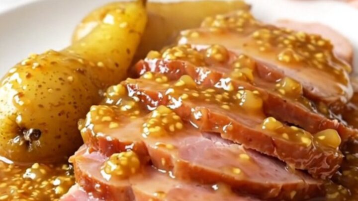 A platter featuring thick, succulent slices of slow-cooked ham arranged neatly next to tender, glazed pear halves.