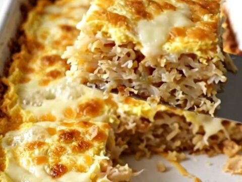A golden, bubbling French onion hash brown breakfast casserole in a white ceramic dish.