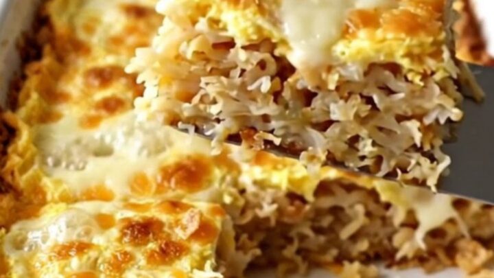 A golden, bubbling French onion hash brown breakfast casserole in a white ceramic dish.