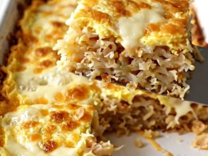 A golden, bubbling French onion hash brown breakfast casserole in a white ceramic dish.