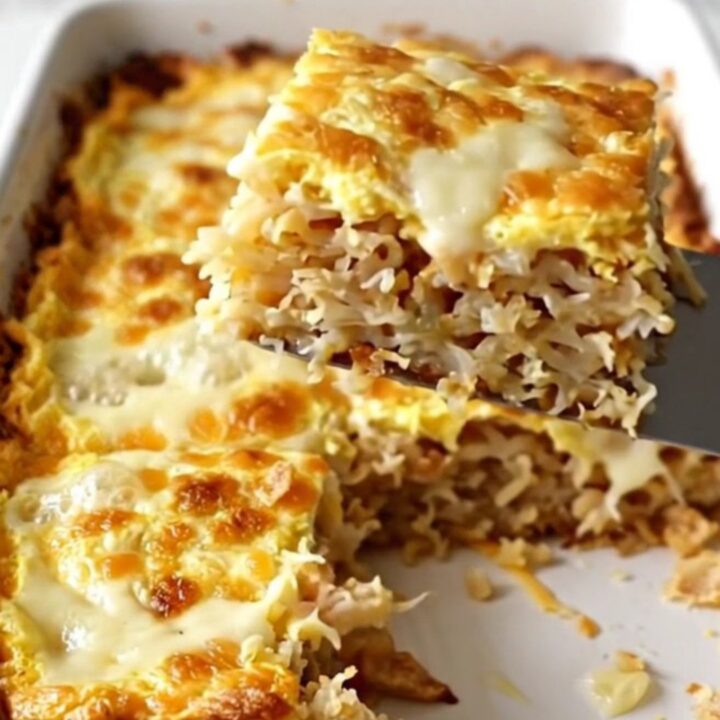 A golden, bubbling French onion hash brown breakfast casserole in a white ceramic dish.