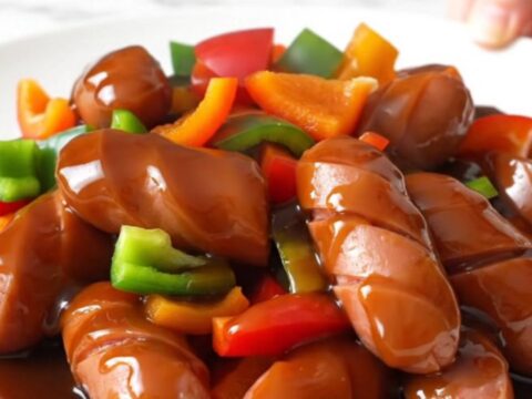 A close-up of slow cooker teriyaki chicken sausage with bell peppers and pineapple in a glossy glaze.