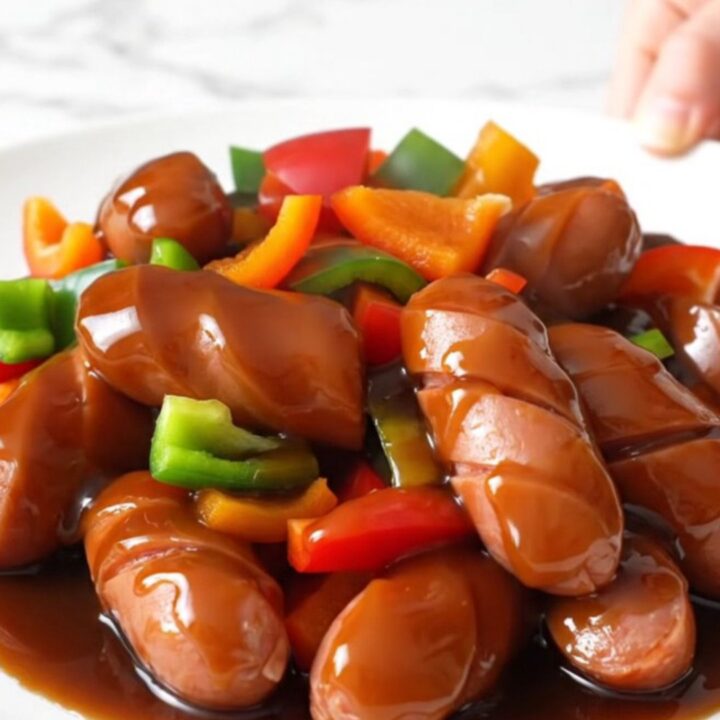 A close-up of slow cooker teriyaki chicken sausage with bell peppers and pineapple in a glossy glaze.